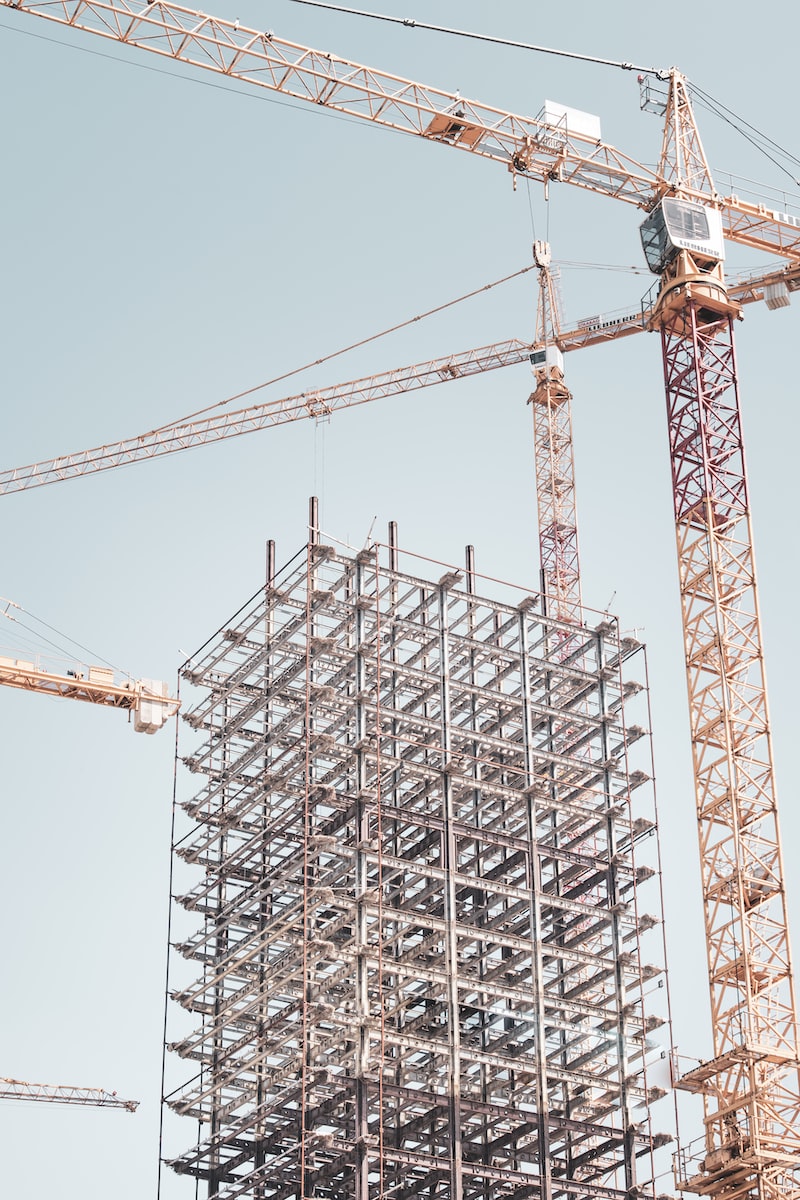 gray metal building frame near tower crane during daytime